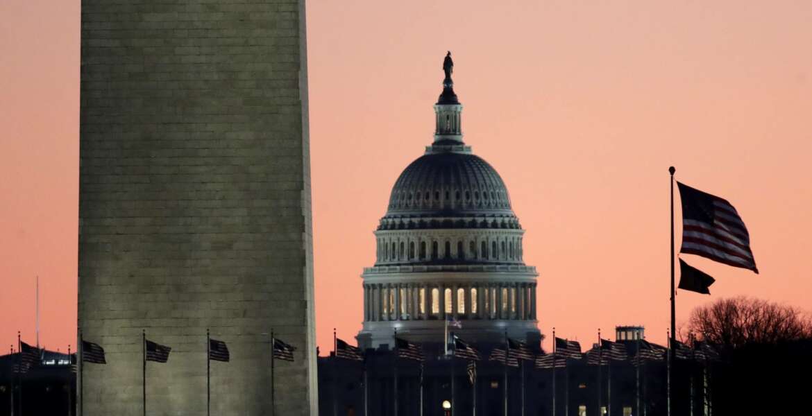 The U.S. Capitol building, center, is seen next to the bottom part of the Washington Monument, left, before sunrise on Capitol Hill in Washington, Thursday, Dec. 19, 2019, a day after the U.S. House voted to impeach President Donald Trump on two charges, abuse of power and obstructing Congress. (AP Photo/Julio Cortez)
