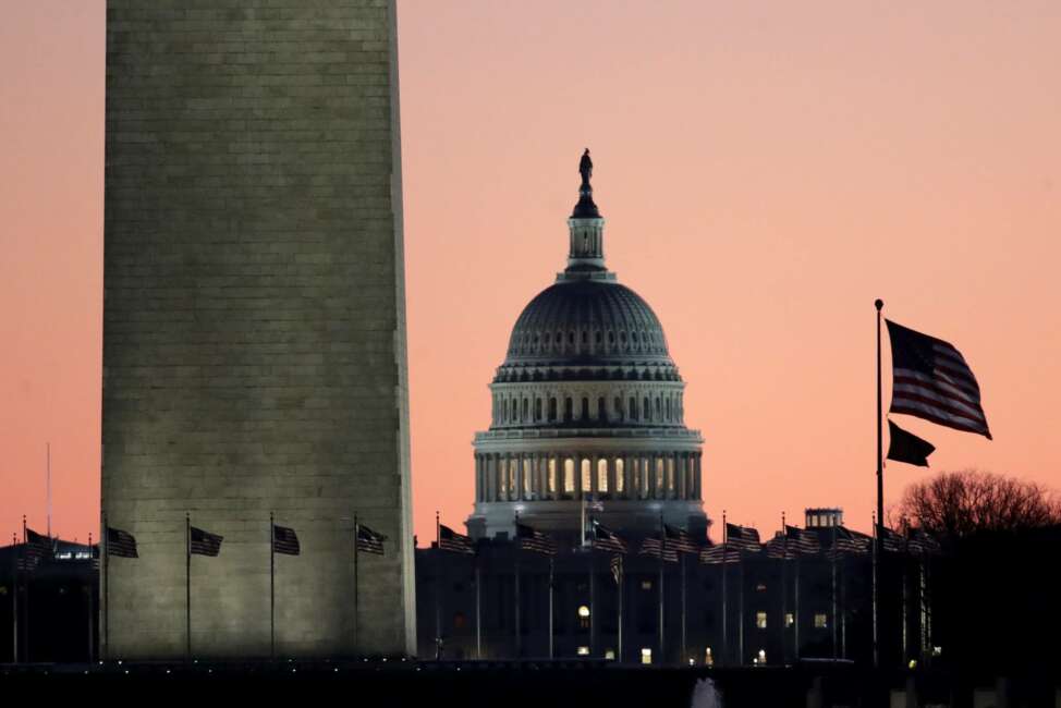 The U.S. Capitol building, center, is seen next to the bottom part of the Washington Monument, left, before sunrise on Capitol Hill in Washington, Thursday, Dec. 19, 2019, a day after the U.S. House voted to impeach President Donald Trump on two charges, abuse of power and obstructing Congress. (AP Photo/Julio Cortez)