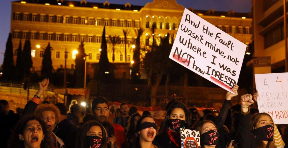 Protesters chant placards during a demonstration to protest sexual harassment and bullying and demanding rights, in front of the government house in downtown Beirut, Lebanon, Saturday, Dec. 7, 2019. Scores of women marched through the streets to protest sexual harassment and bullying and demanding rights including the passing of citizenship to children of Lebanese women married to foreigners. (AP Photo/Bilal Hussein)