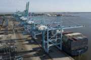 FILE - In this Friday, May 10, 2019 file photo, A container ship is unloaded at the Virginia International Gateway terminal in Norfolk, Va.  Defying fears and predictions, the American job market is still shrugging off President Donald Trump’s trade wars. Employers added an impressive 266,000 jobs in November, and unemployment returned to a 50-year low 3.5% _ all at a time when the Trump administration is engaged in a bruising trade war with China while fighting other U.S. trading partners as well. (AP Photo/Steve Helber, File)