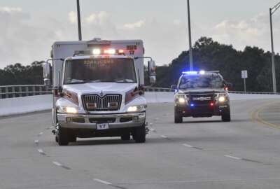 Police cars escort an ambulance after a shooter open fire inside the Pensacola Air Base, Friday, Dec. 6, 2019 in Pensacola, Fla.   The US Navy is confirming that a shooter is dead and several injured after gunfire at the Naval Air Station in Pensacola.  (Tony Giberson/ Pensacola News Journal via AP)