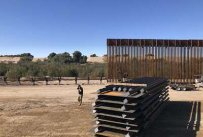 In this Jan. 10, 2020, photo, people work at a portion of border wall which is under construction in Yuma, Ariz. Illegal border crossings have plummeted as the Trump administration has extended a policy to make asylum seekers wait in Mexico for court hearings in the U.S. (AP Photo/Elliot Spagat)