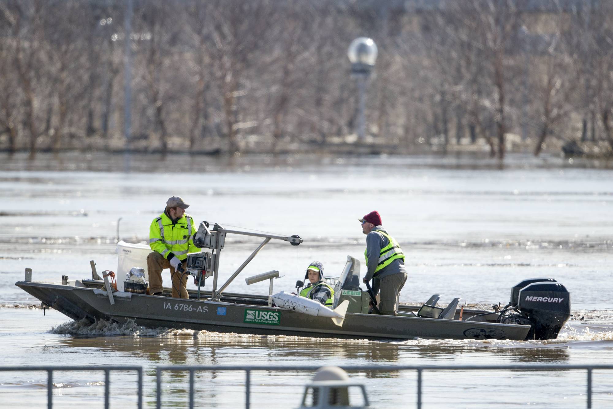FILE- In this March 16, 2019 file photo, surveyors with the USGS take measurements of the Missouri River in Omaha, Neb., as the river overflows its banks. Nebraska, Iowa, Kansas and Missouri are joining forces for a study that will look for ways the states can limit flooding along the Missouri River and give them information about how wetter weather patterns could require changes to the federal government's management of the basin's reservoirs. The states are pooling their money to pay for half of a $400,000 study with the U.S. Army Corps of Engineers to measure how much water flows down the Missouri River. (AP Photo/Nati Harnik)