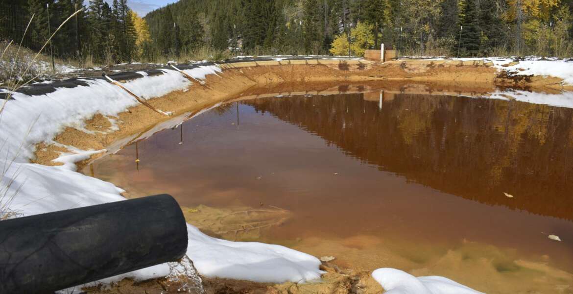FILE - In this Oct. 12, 2018 file photo, water contaminated with arsenic, lead and zinc flows from a pipe out of the Lee Mountain mine and into a holding pond near Rimini, Mont. The community is part of the Upper Tenmile Creek Superfund site, where dozens of abandoned mines have left water supplies polluted and residents must use bottled water. The Trump administration has built up the largest backlog of unfunded toxic Superfund projects awaiting clean-up in at least 15 years, nearly tripling the number of sites where clean-ups are ready to go but awaiting money, according to 2019 figures quietly released by the Environmental Protection Agency over the winter holidays. (AP Photo/Matthew Brown)