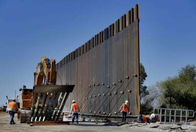 FILE - In this Sept. 10, 2019 file photo, government contractors erect a section of Pentagon-funded border wall along the Colorado River in Yuma, Ariz. Defense officials say the Department of Homeland Security has asked the Pentagon to fund the construction of 270 miles of border wall this year as part of a counter-drug effort.  (AP Photo/Matt York)