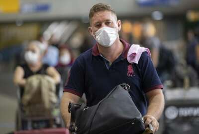 A man wears a mask as a precaution against the spread of the new coronavirus COVID-19 after his plane landed at the Sao Paulo International Airport in Sao Paulo, Brazil, Thursday, Feb. 27, 2020. (AP Photo/Andre Penner)