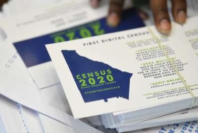 FILE - In this Aug. 13, 2019, file photo, a worker gets ready to pass out instructions on how to fill out the 2020 census during a town hall meeting in Lithonia, Ga. Because of the new coronavirus, the U.S. Census Bureau has postponed sending out census takers to count college students in off-campus housing and delayed sending workers to grocery stores and houses of worship where they help people fill out the once-a-decade questionnaire.  The Census Bureau said in a statement Sunday, March 15, 2020, that the deadline for ending the 2020 census at the end of July could be adjusted as needed.  (AP Photo/John Amis, File)
