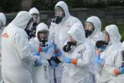 Workers from a Servpro disaster recovery team wearing protective suits and respirators are given supplies as they line up before entering the Life Care Center in Kirkland, Wash., to begin cleaning and disinfecting the facility, Wednesday, March 11, 2020. The nursing home is at the center of the coronavirus outbreak in Washington state. For most people, the virus causes only mild or moderate symptoms. For some it can cause more severe illness, especially in older adults and people with existing health problems. (AP Photo/Ted S. Warren)