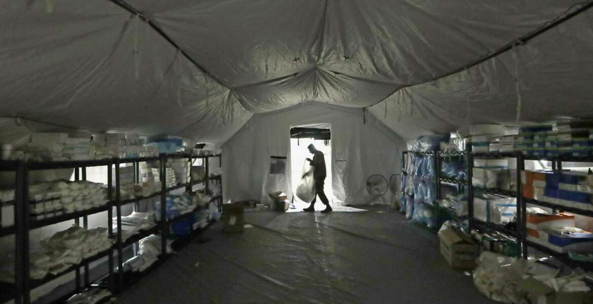 A U.S. Army soldier walks inside a mobile surgical unit being set up by soldiers from Fort Carson, Col., and Joint Base Lewis-McChord (JBLM) as part of a field hospital inside CenturyLink Field Event Center, Tuesday, March 31, 2020, in Seattle. Soldiers from the 627th Army Hospital at Fort Carson, will join soldiers from JBLM to staff the 250-bed hospital to be used for non-COVID-19 cases, allowing local hospitals additional space for patients affected by the coronavirus outbreak. Officials said that the field hospital is expected to be ready to receive patients next week. (AP Photo/Elaine Thompson)