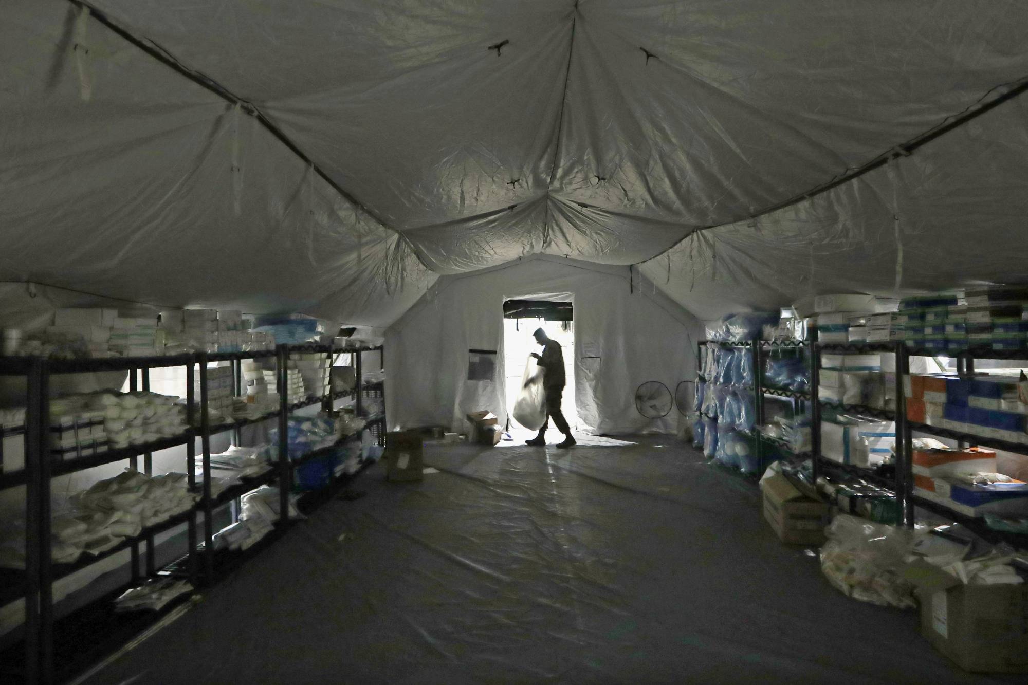 A U.S. Army soldier walks inside a mobile surgical unit being set up by soldiers from Fort Carson, Col., and Joint Base Lewis-McChord (JBLM) as part of a field hospital inside CenturyLink Field Event Center, Tuesday, March 31, 2020, in Seattle. Soldiers from the 627th Army Hospital at Fort Carson, will join soldiers from JBLM to staff the 250-bed hospital to be used for non-COVID-19 cases, allowing local hospitals additional space for patients affected by the coronavirus outbreak. Officials said that the field hospital is expected to be ready to receive patients next week. (AP Photo/Elaine Thompson)