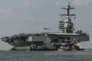 FILE - In this April 14, 2017 file photo, as crew members stand on the deck, the aircraft carrier USS Gerald R. Ford heads to the Norfolk, Va., naval station. Toilets on the USS Gerald R. Ford and USS George H.W. Bush  carriers that have become repeatedly clogged could require treatments costing $400,000 each to get them working properly, a U.S. Government Accountability Office report found.  (Bill Tiernan/The Virginian-Pilot via AP, File)