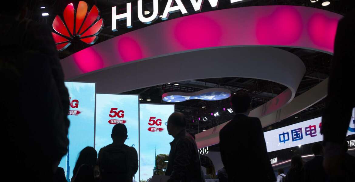 FILE - In this Oct. 31, 2019, file photo, attendees walk past a display for 5G services from Chinese technology firm Huawei at the PT Expo in Beijing. Chinese tech giant Huawei says its 2019 sales rose 19.1% over a year earlier despite U.S. sanctions that hampered its smartphone and network equipment businesses. (AP Photo/Mark Schiefelbein, File)