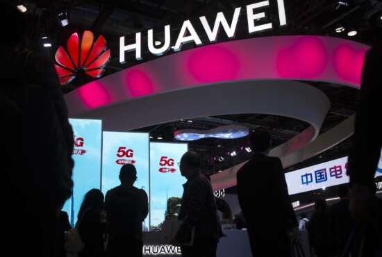 FILE - In this Oct. 31, 2019, file photo, attendees walk past a display for 5G services from Chinese technology firm Huawei at the PT Expo in Beijing. Chinese tech giant Huawei says its 2019 sales rose 19.1% over a year earlier despite U.S. sanctions that hampered its smartphone and network equipment businesses. (AP Photo/Mark Schiefelbein, File)