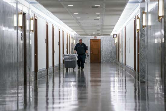 A workman walks through the empty corridors of the Dirksen Senate Office Building on Capitol Hill as lawmakers negotiate on the emergency coronavirus response legislation, in Washington, Wednesday, March 18, 2020. (AP Photo/J. Scott Applewhite)