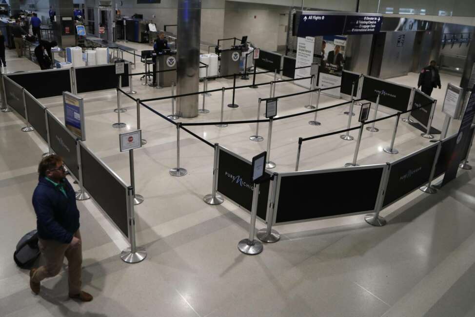 An airline passenger walks by the vacant TSA checkin at the Detroit Metropolitan Airport, Monday, March 23, 2020, in Romulus, Mich. The COVID-19 coronavirus has considerably slowed air travel. (AP Photo/Carlos Osorio)