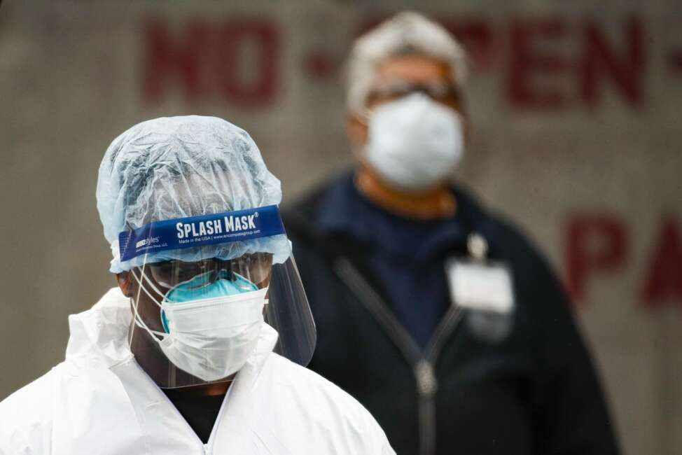 Medical workers wearing personal protective equipment due to COVID-19 concerns pause for rest before loading bodies into a refrigerated container truck functioning as a makeshift morgue, Tuesday, March 31, 2020, at Brooklyn Hospital Center in Brooklyn borough of New York. The new coronavirus causes mild or moderate symptoms for most people, but for some, especially older adults and people with existing health problems, it can cause more severe illness or death. (AP Photo/John Minchillo)