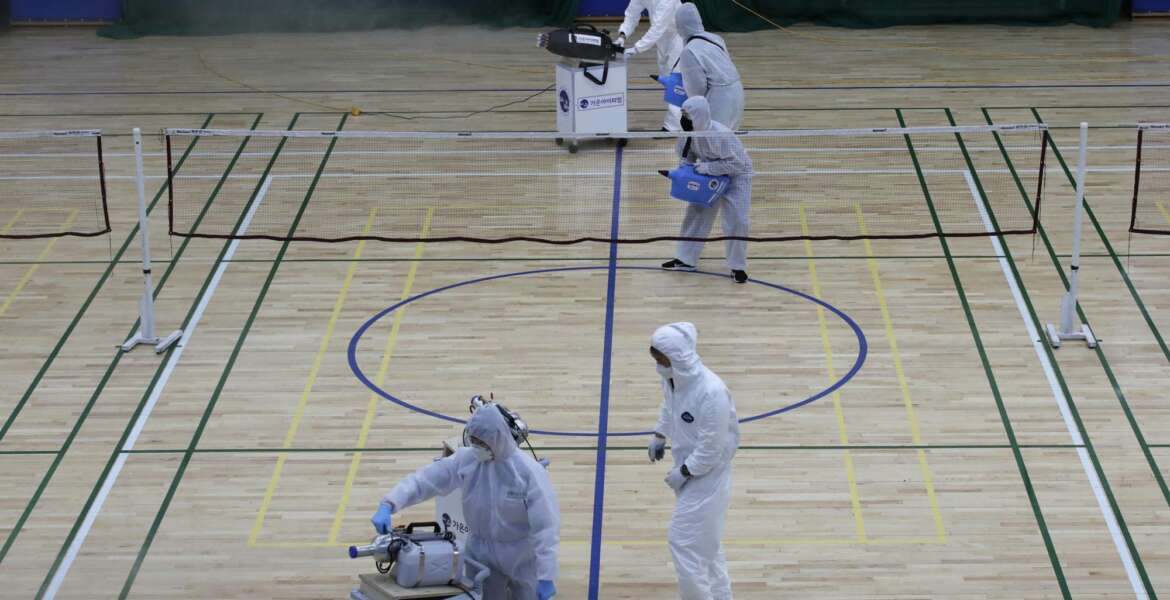 In this Feb. 25, 2020, file photo, workers in protective suits spray disinfectant as a precaution against the COVID-19 at an indoor gymnasium in Seoul, South Korea. As the coronavirus spreads around the world, many events that normally would draw large numbers of people are being canceled or played without fans. (AP Photo/Lee Jin-man, File)