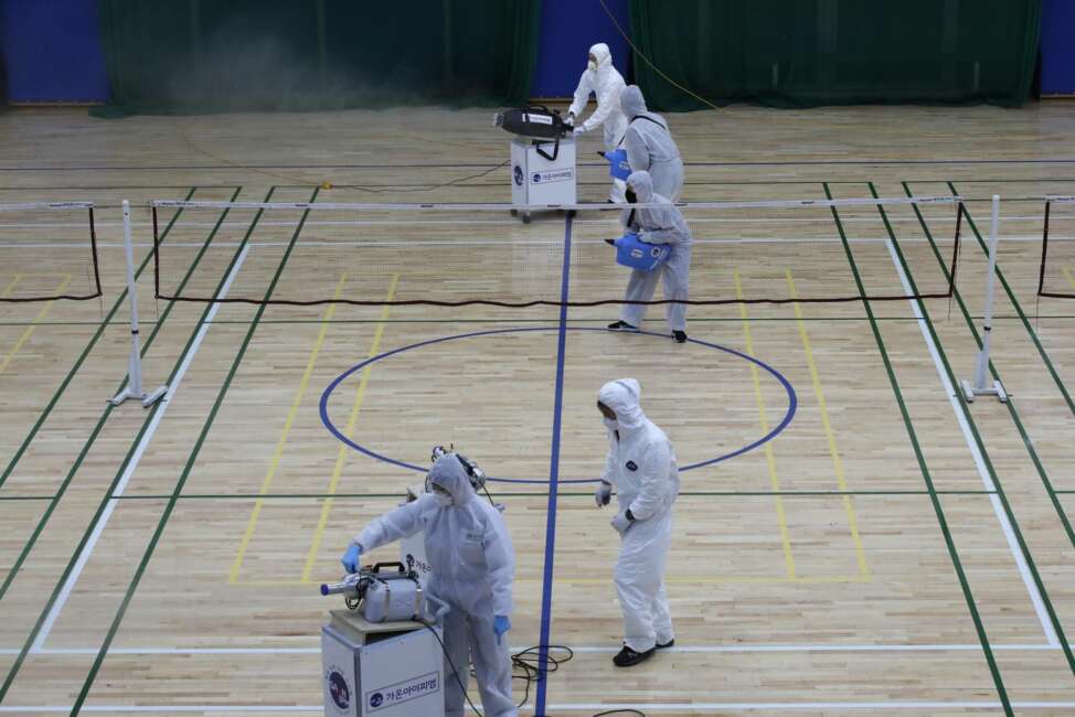 In this Feb. 25, 2020, file photo, workers in protective suits spray disinfectant as a precaution against the COVID-19 at an indoor gymnasium in Seoul, South Korea. As the coronavirus spreads around the world, many events that normally would draw large numbers of people are being canceled or played without fans. (AP Photo/Lee Jin-man, File)