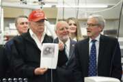 President Donald Trump holds a photograph of coronavirus as Dr. Steve Monroe,right, with CDC speaks to members of the press at the headquarters of the Centers for Disease Control and Prevention in Atlanta on Friday, March 6, 2020. President Trump's trip to the Centers for Disease Control and Prevention, briefly scuttled Friday because of unfounded fears that someone there had contracted the coronavirus, was back on, giving the president another chance to calm growing alarm about the spread of the virus in America.  (Hyosub Shin/Atlanta Journal-Constitution via AP)