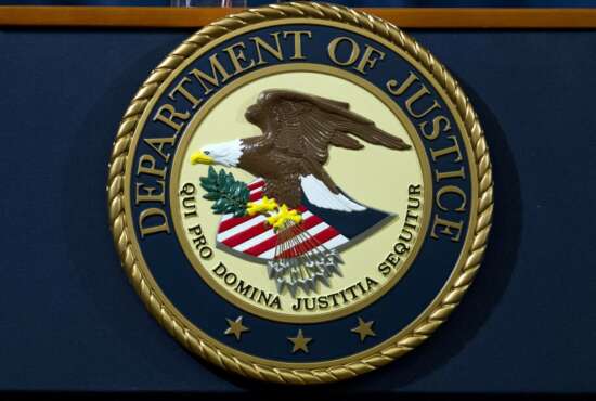 FILE - In this Nov. 28, 2018, file photo, the Department of Justice seal is seen in Washington, D.C. An internet firm is ending the automated registration of website names that include words or phrases related to the COVID-19 pandemic, in an attempt to combat coronavirus-related fraud. Los Angeles-based Namecheap Inc. made the pledge after a federal judge in Texas on Sunday, March 22, 2020, ordered the takedown of a website the U.S. Department of Justice accused of stealing credit card information while offering fake coronavirus vaccine kits. (AP Photo/Jose Luis Magana, File)