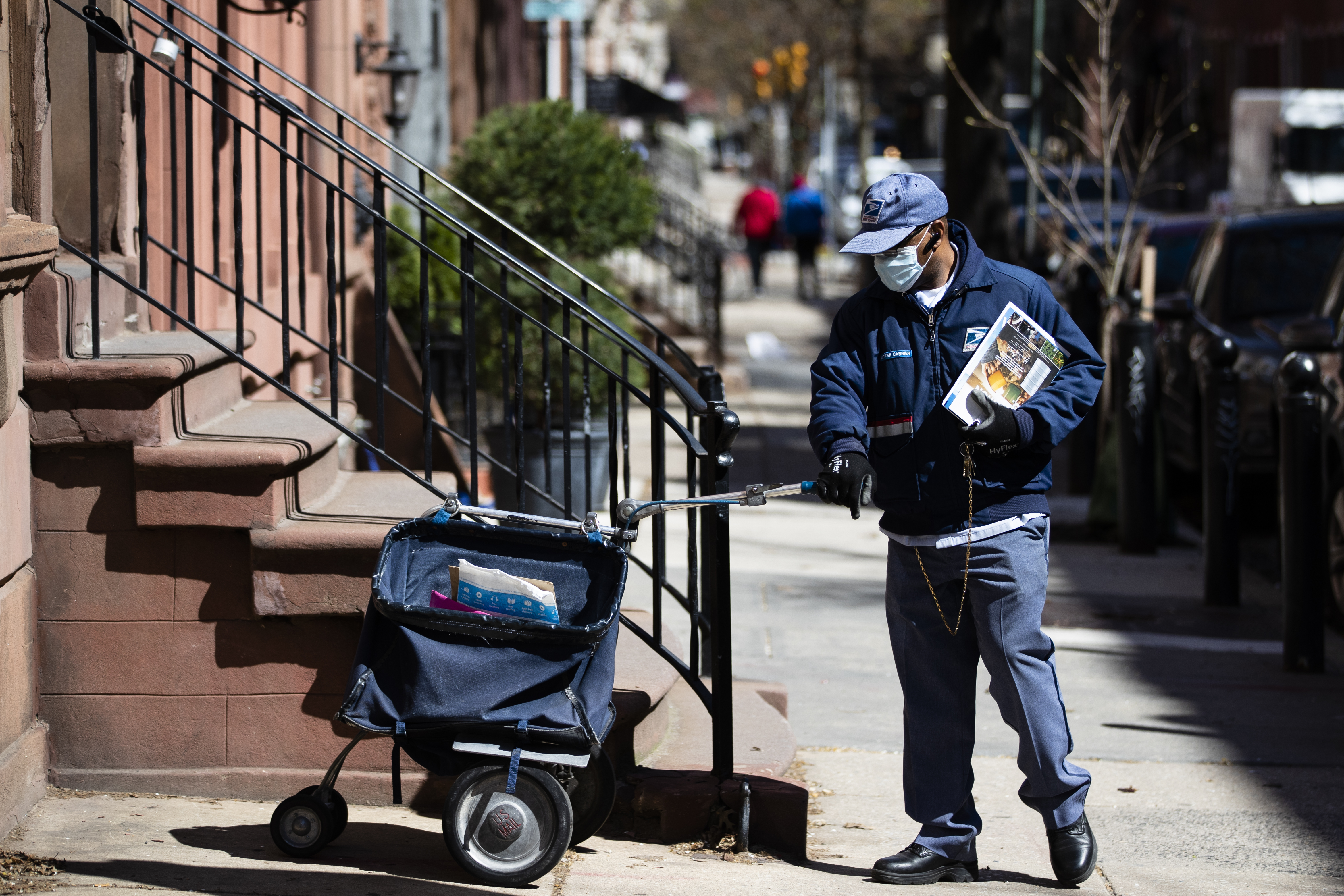 A United States Postal worker makes a delivery with gloves and a mask in Philadelphia, Thursday, April 2, 2020. The U.S. Postal Service is keeping post offices open but ensuring customers stay at least 6 feet (2 meters) apart. The agency said it is following guidance from public health experts, although there is no indication that the new coronavirus COVID-19 is being spread through the mail. (AP Photo/Matt Rourke)
