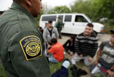 FILE - In this Thursday, March 14, 2019, file photo, a Border Patrol agent talks with a group suspected of having entered the U.S. illegally near McAllen, Texas. The Trump administration has quietly shut down the nation's asylum system for the first time in decades amid coronavirus concerns, largely because holding people in custody is considered too dangerous. (AP Photo/Eric Gay, File)