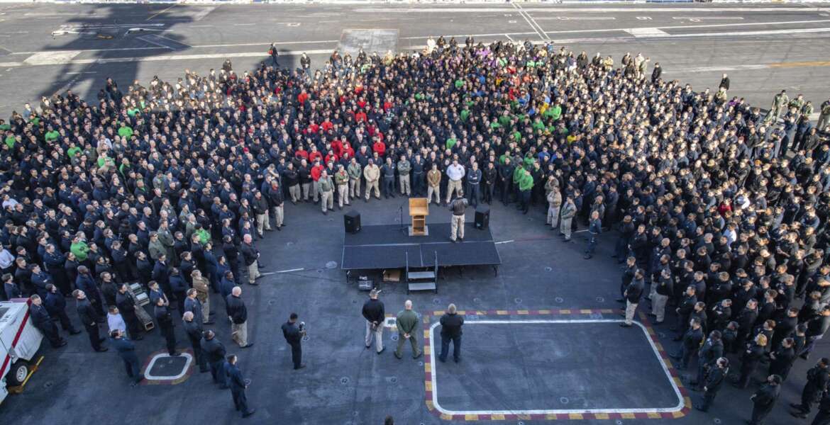 In this Dec. 15, 2019, photo U.S.Navy Capt. Brett Crozier, commanding officer of the aircraft carrier USS Theodore Roosevelt (CVN 71), addresses the crew during an all hands call on the ship's flight deck while conducting routine training in the Eastern Pacific Ocean. U.S. defense leaders are backing the Navy's decision to fire the ship captain who sought help for his coronavirus-stricken aircraft carrier, even as videos showed his sailors cheering him as he walked off the vessel. Videos went viral on social media Friday, April 3, 2020, showing hundreds of sailors gathered on the ship chanting and applauding Navy Capt. Brett Crozier as he walked down the ramp, turned, saluted, waved and got into a waiting car. (U.S. Navy Photo by Mass Communication Specialist Seaman Kaylianna Genier via AP)