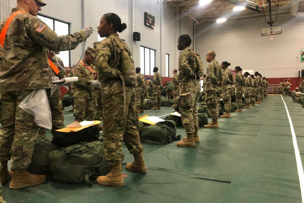 In this image provided by the U.S. Army, recent Army basic combat training graduates have their temperatures taken as they arrive at Fort Lee, Va, on March 31, 2020, after being transported using sterilized buses from Fort Jackson, S.C. (U.S. Army via AP)