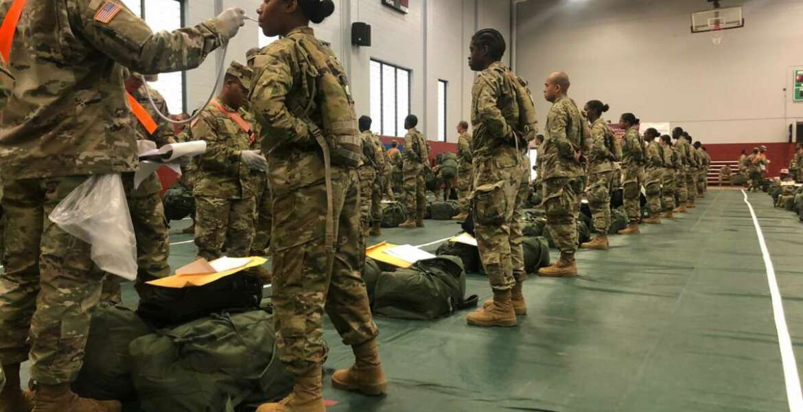 In this image provided by the U.S. Army, recent Army basic combat training graduates have their temperatures taken as they arrive at Fort Lee, Va, on March 31, 2020, after being transported using sterilized buses from Fort Jackson, S.C. (U.S. Army via AP)