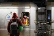 A MTA employee, wears a mask to protect against coronavirus,  waits in the conductors area of a subway car as NYPD and MTA officers wake up sleeping passengers and direct them to the exits at the 207th Street A-train station, Thursday, April 30, 2020, in the Manhattan borough of New York. (AP Photo/John Minchillo)