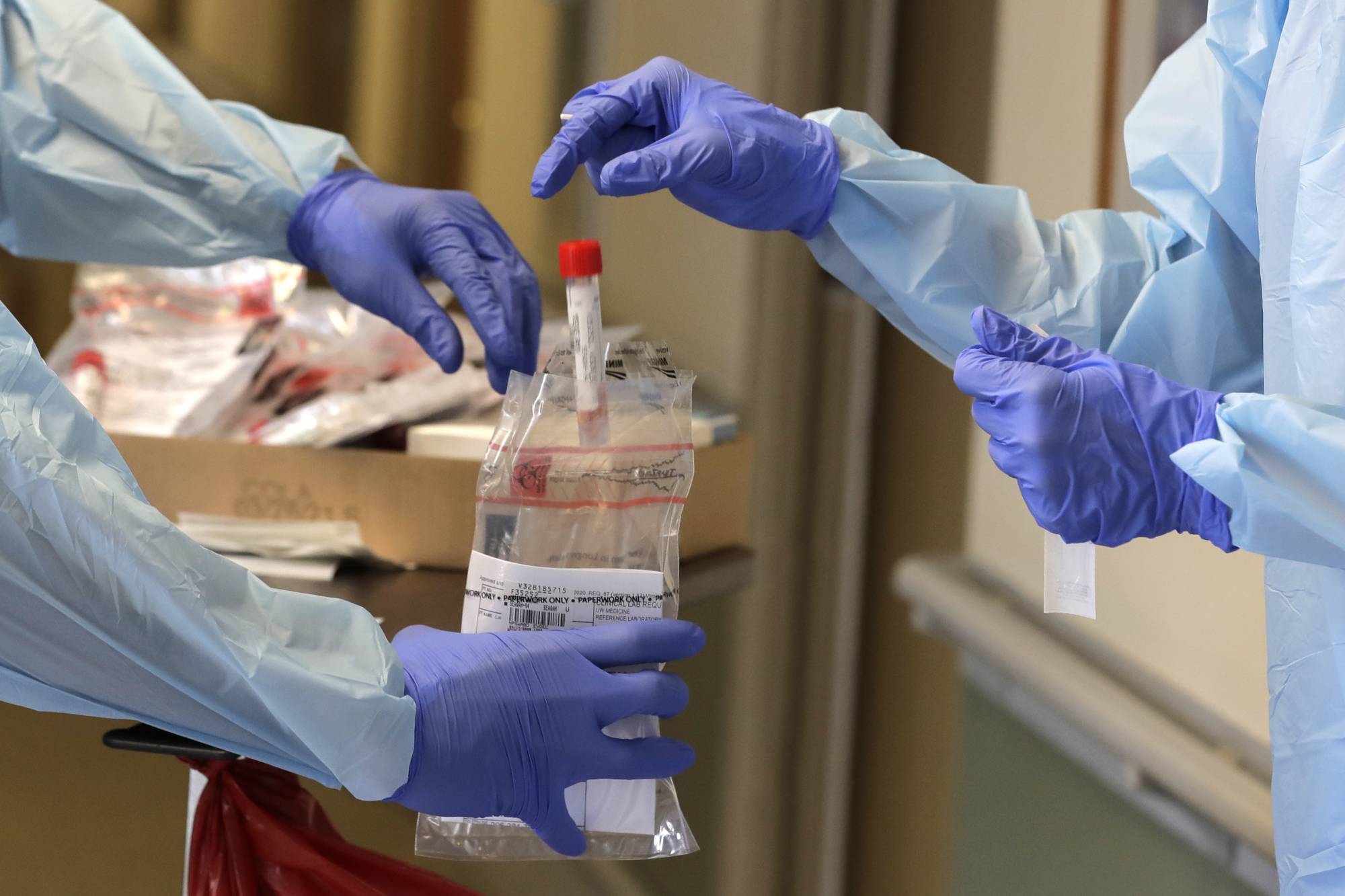 In this Friday, April 17, 2020, photo, a vial used to collect a nose swab sample is put into a collection bag as members of a team of University of Washington medical providers conduct coronavirus testing at Queen Anne Healthcare, a skilled nursing and rehabilitation facility in Seattle. More than 100 residents were tested during the visit, and the results for all were negative, according to officials. (AP Photo/Ted S. Warren)
