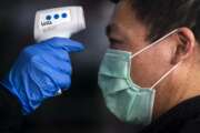 A staff worker checks the body temperature of a customer before enter in a supermarket in Madrid, Spain, Spain, Wednesday, April 29, 2020 as the lockdown to combat the spread of coronavirus continues. Official statistics show that Spain's unemployment rate rose to 14.4% in the first quarter of 2020, reflecting only the partial impact of the new coronavirus pandemic in Spain's job market. Spain's left-wing coalition government is poised to announce Tuesday further steps to ease the 7-week lockdown, one of the world's strictest. (AP Photo/Manu Fernandez)