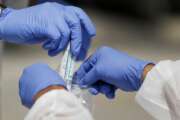 FILE - In this April 16, 2020, file photo, vials containing nasal swabs collected at a COVID-19 drive-through testing site are dropped into a plastic bag to be sent off for processing after being collected in St. Louis. An Associated Press review of more than 20 states found that before the coronavirus outbreak many had at least a modest supply of N95 masks, gowns, gloves and other medical equipment. But those supplies often were well past their expiration dates, left over from the H1N1 influenza outbreak a decade ago. (AP Photo/Jeff Roberson, File)