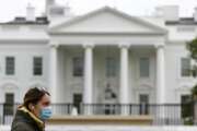 FILE - In this April 1, 2020, file photo a woman wearing a face mask walks past the White House in Washington. The nation's capital, like most of the nation itself, is largely shuttered. (AP Photo/Patrick Semansky, File)