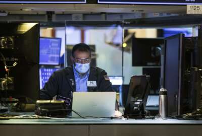 In this photo provided by the New York Stock Exchange, trader Aman Patel wears a protective face mask as he works on the partially reopened trading floor, Tuesday, May 26, 2020. Stocks surged on Wall Street in afternoon trading Tuesday, driving the S&P 500 to its highest level in nearly three months, as hopes for economic recovery overshadow worries about the coronavirus pandemic. (Colin Zimmer/New York Stock Exchange via AP)