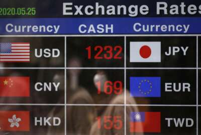 A woman wearing a face mask is reflected on an electronic foreign currency exchange rates in downtown Seoul, South Korea, Monday, May 25, 2020. Asian shares are mostly higher, with Tokyo stocks gaining on expectations that a pandemic state of emergency will be lifted for all of Japan. But shares fell in Hong Kong on Monday after police used tear gas to quell weekend protests over a proposed national security bill for the former British colony. (AP Photo/Lee Jin-man)
