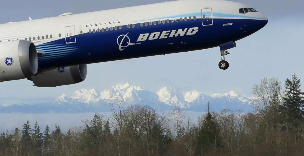 FILE - In this Jan. 25, 2020, file photo a Boeing 777X airplane takes off on its first flight with the Olympic Mountains in the background at Paine Field in Everett, Wash.  Boeing on Wednesday, May 27, is cutting more than 12,000 jobs through layoffs and buyouts as the coronavirus pandemic seizes the travel industry. And the aircraft maker says more cuts are coming.  (AP Photo/Ted S. Warren, File).
