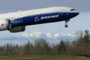 FILE - In this Jan. 25, 2020, file photo a Boeing 777X airplane takes off on its first flight with the Olympic Mountains in the background at Paine Field in Everett, Wash.  Boeing on Wednesday, May 27, is cutting more than 12,000 jobs through layoffs and buyouts as the coronavirus pandemic seizes the travel industry. And the aircraft maker says more cuts are coming.  (AP Photo/Ted S. Warren, File).