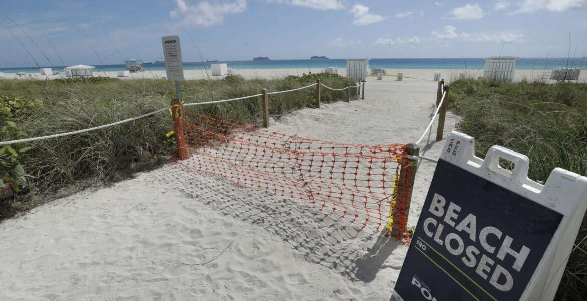 FILE - In this Tuesday, March 31, 2020 file photo, an entrance to a beach is shown closed, in Miami Beach, Florida's famed South Beach. Memorial Day weekend historically signifies the start of the summer vacation season as families throughout the U.S. plan trips to Florida's beaches and theme parks. Miami-Dade County officials aren't expecting crowds, as the beaches remain closed. (AP Photo/Wilfredo Lee, File)