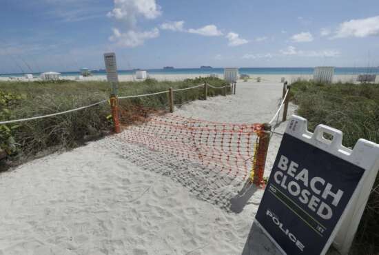 FILE - In this Tuesday, March 31, 2020 file photo, an entrance to a beach is shown closed, in Miami Beach, Florida's famed South Beach. Memorial Day weekend historically signifies the start of the summer vacation season as families throughout the U.S. plan trips to Florida's beaches and theme parks. Miami-Dade County officials aren't expecting crowds, as the beaches remain closed. (AP Photo/Wilfredo Lee, File)