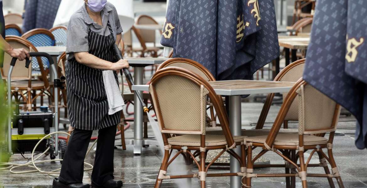 In this May 27, 2020, photo, a worker at Brasserie Beck, a restaurant along K Street in downtown Washington, power washes the outdoor seating area. The nation's capital is starting to reopen, Starting May 29, a tiny slice of pre-pandemic normality starts returning to the city as the three-month old coronavirus stay-home order is replaced by the first phase of a reopening plan(AP Photo/Jon Elswick)