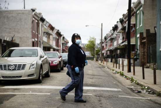 United States Postal Service carrier Henrietta Dixon walks her route to deliver mail in Philadelphia, Wednesday, May 6, 2020. From coastal Maine to Philadelphia's close-knit neighborhoods, many residents call the service essential to their communities. (AP Photo/Matt Rourke)