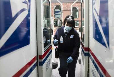 In this Wednesday, May 6, 2020, photo, United States Postal Service carrier Henrietta Dixon gets into her truck to deliver mail in Philadelphia. (AP Photo/Matt Rourke)