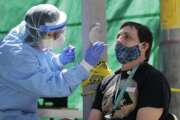 FILE - In this May 16, 2020, file photo, Tina Nguyen, left, a nurse at the International Community Health Services clinic in Seattle's International District, takes a nose swab sample from David Carroll, an ICHS employee, during testing for the coronavirus in Seattle. At a cost of $120-130 per test and NHL Commissioner Gary Bettman’s estimate the league will need 25,000-35,000 in total to get through the playoffs, the price tag he concedes is “millions of dollars.” But regular testing is something players insisted on in the name of feeling safe to compete.(AP Photo/Ted S. Warren, File)