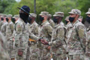 U.S. Air Force Tech. Sgt. Rashawn Duffy, 37th Training Wing Detachment 5 military training instructor, presents a coin to an Airman during the basic military training coining ceremony outside of Erwin Manor at Keesler Air Force Base, Mississippi, May 14, 2020. Nearly 60 Airmen from the 37th TRW Detachment 5 completed the six-week basic military training course. Due to safety concerns stemming from COVID-19, the Air Force sent new recruits to Keesler to demonstrate a proof of concept to generate the force at multiple locations during contingencies. The flight was the first to graduate BMT at Keesler since 1968. (U.S. Air Force photo by Kemberly Groue)