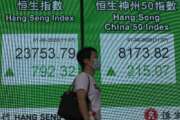 A woman wearing a face mask walks past a bank electronic board showing the Hong Kong share index at Hong Kong Stock Exchange Monday, June 1, 2020. Asian stock markets have rebounded after U.S. President Donald Trump avoided reigniting a trade war with China amid tension. (AP Photo/Vincent Yu)