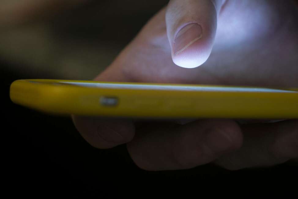 FILE - In this Aug. 11, 2019, file photo, a man uses a cell phone in New Orleans. The U.S. communications regulator on Tuesday, June 9, 2020, proposed a $225 million fine, its largest ever, against two health insurance telemarketers for spamming people with 1 billion robocalls using fake phone numbers. (AP Photo/Jenny Kane, File)