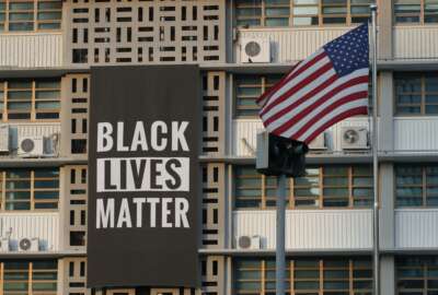 In this June 14, 2020 photo, U.S. flag flutters next to a giant Black Lives Matter banner at the U.S. Embassy in Seoul, South Korea. The  banner has been removed from the U.S. Embassy building in South Korea's capital three days after it was raised there in solidarity with protesters back home.(AP Photo/Lee Jin-man)