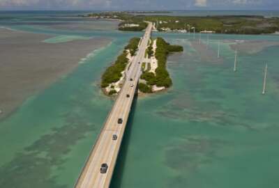 In this drone aerial photo provided by the Florida Keys News Bureau, traffic flows on the Florida Keys Overseas Highway in Islamorada, Fla., towards Key West Monday, June 1, 2020. After being closed to visitors since March 22, 2020, to help curtail the spread of COVID-19, the Florida Keys reopened to tourists Monday. Tourism employs about 45 percent of the Keys workforce. (Andy Newman/Florida Keys News Bureau via AP)