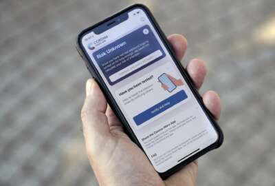 A person holds a smartphone with the official 'Corona Warn-App' (Corona Warning Application) in Berlin, Germany, Monday, June 15, 2020. The app will be introduced on Tuesday, June 16 by the German authorities. (AP Photo/Michael Sohn)